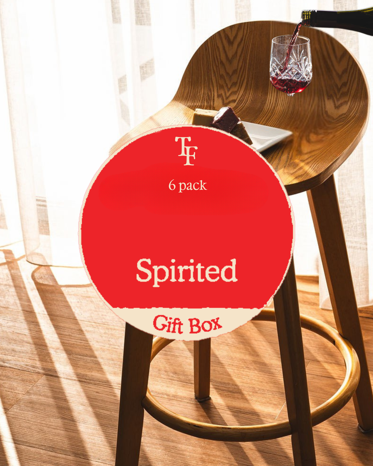 Spirited fudge gift box with wine being poured beside a plate of fudge on a wooden chair in warm sunlight.