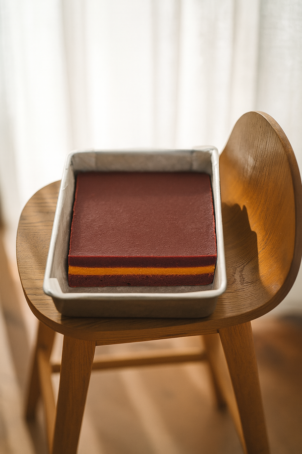 Tray of Sangria Fudge with clean burgundy top layer and bright orange centre stripe, resting on a wooden chair in soft natural light.
